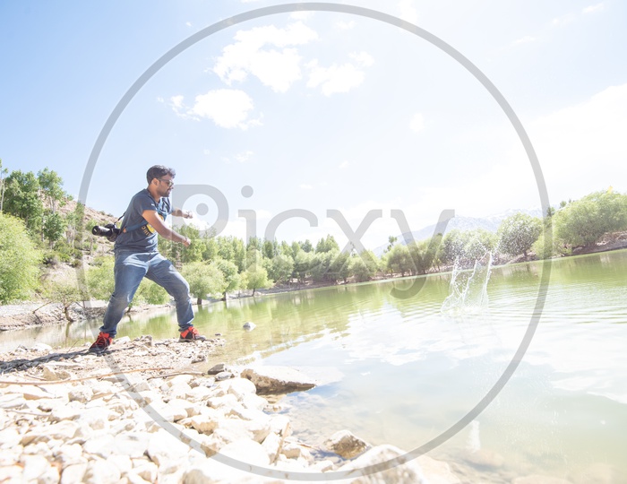 A Man Throwing Stone Over Water Surface at a Lake