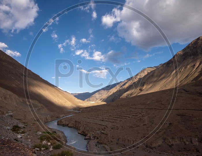 Water Flowing in the River Valleys Of Leh With Cotton Clouds In Blue Sky