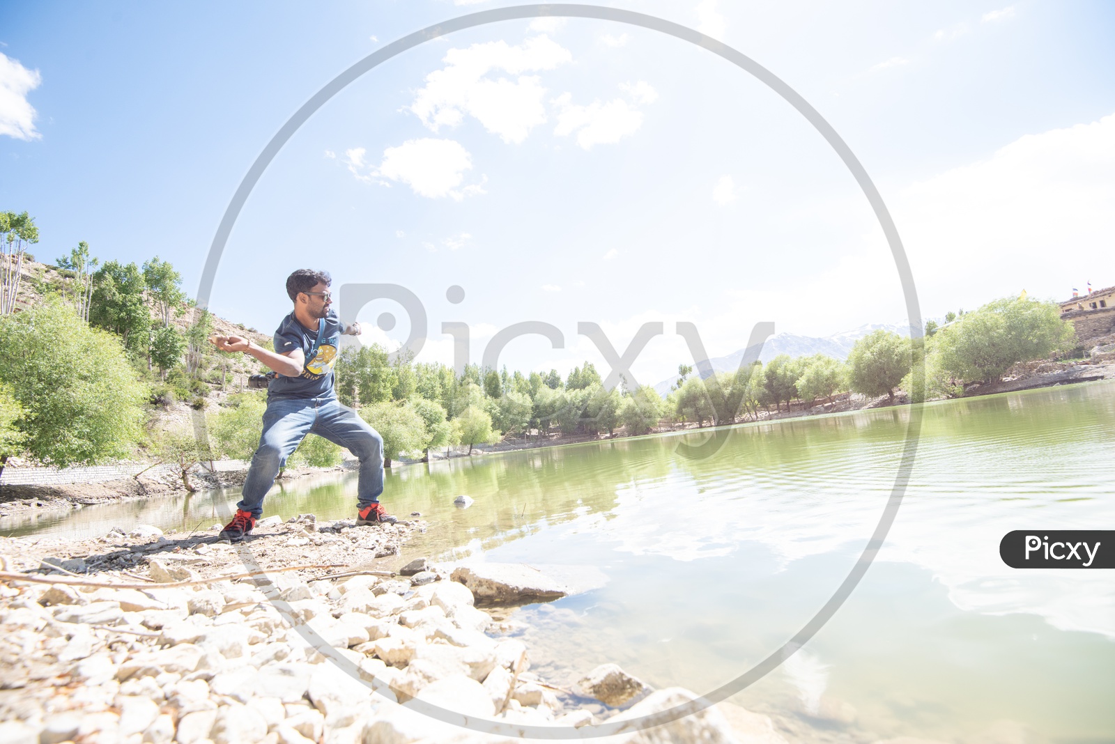 A Man Throwing Stone Over Water Surface at a Lake