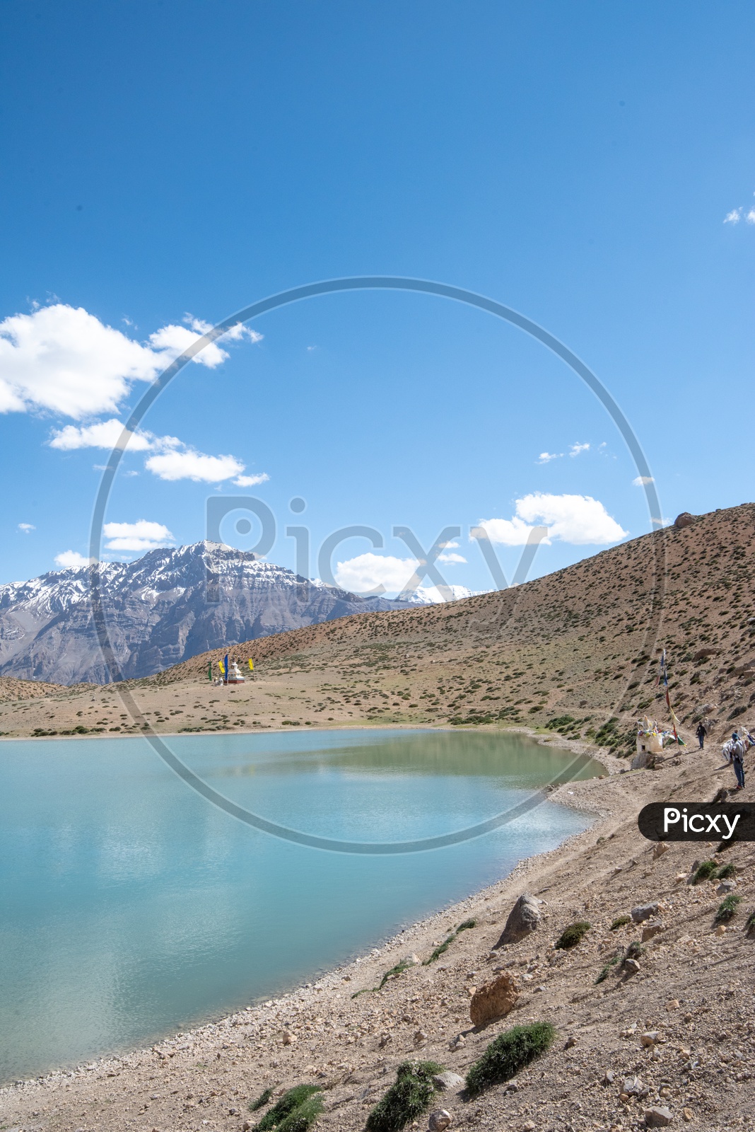 Tourists at Dhankar lake with mountain peaks in the background in Spiti Valley