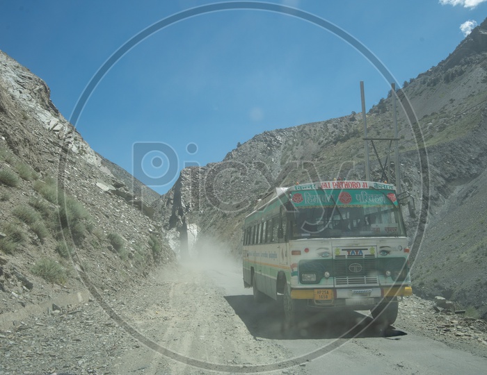 A moving bus on dusty mountain road in Spiti Valley