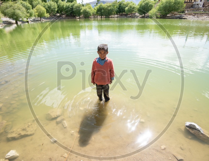 A Young Boy Standing at a Lake In villages of Leh