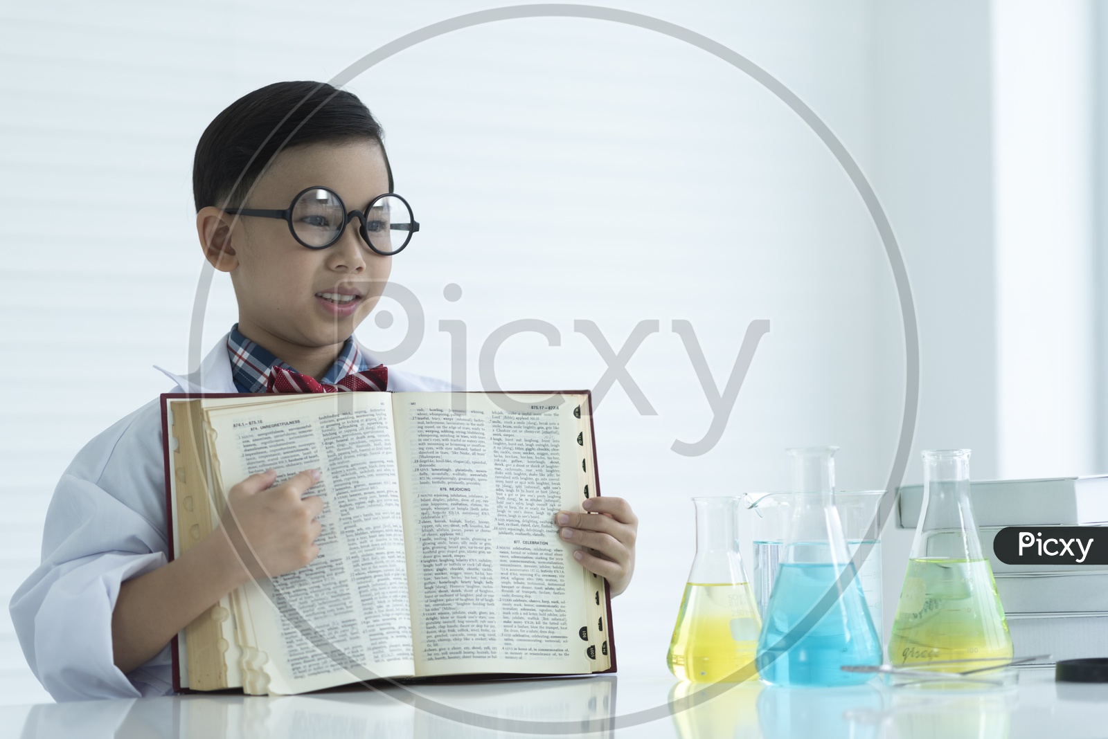 A Young Thai Boy  or Child Student Refering Books Wearing White Apron in a Chemical research Lab