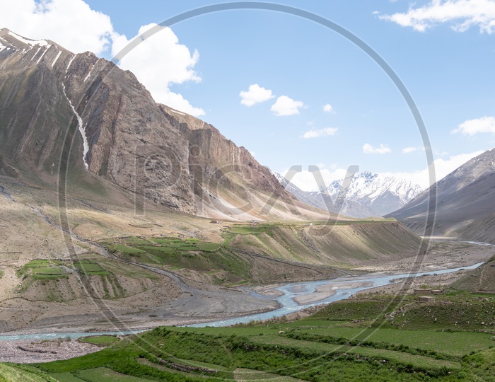 Snow capped Mountains of Spiti Valley with agriculture fields in foreground