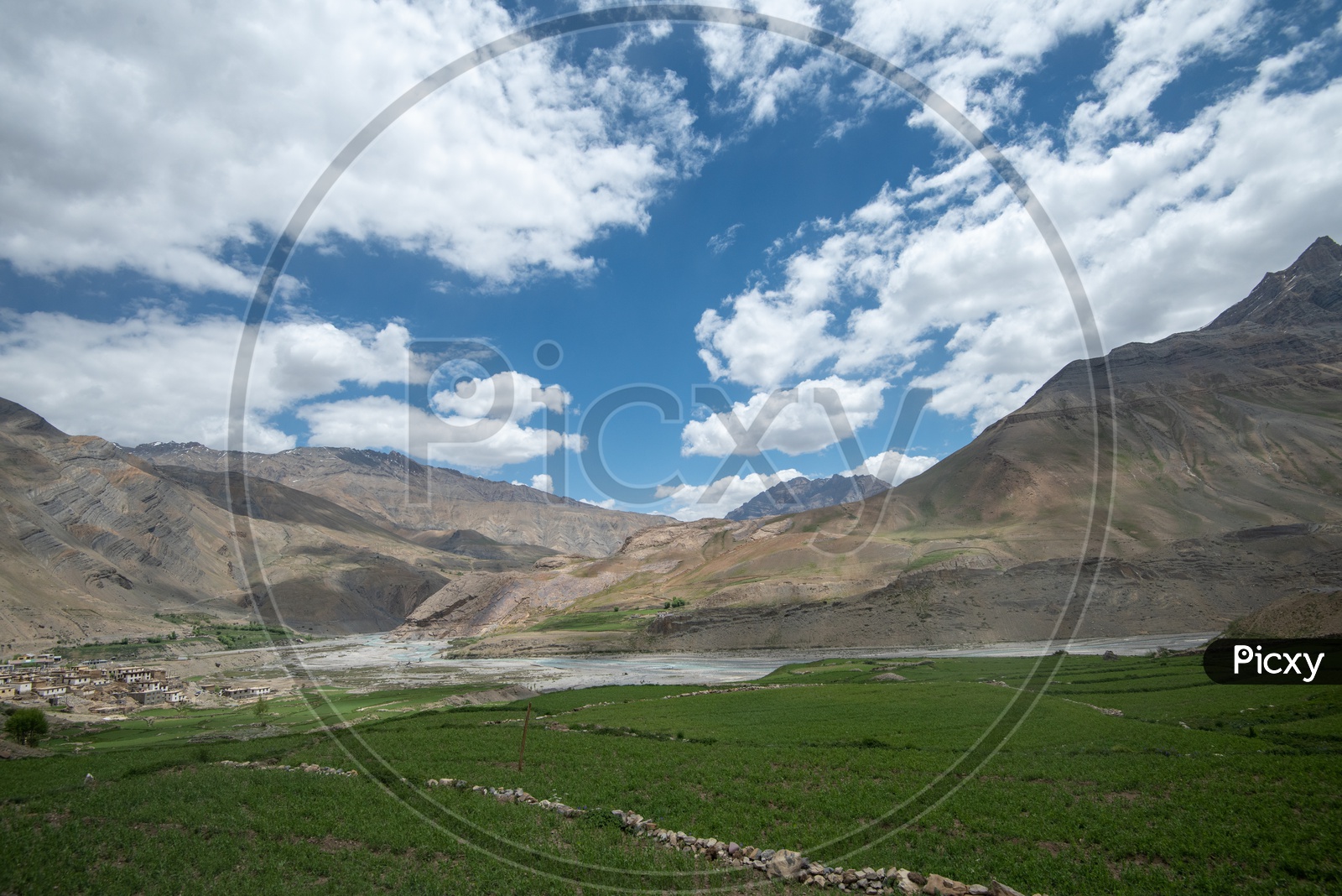 Agricultural farm lands and houses beside Spiti river with mountains in the background