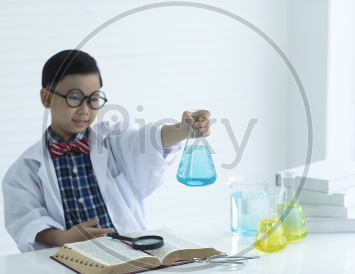 A  Young Thai boy or Child Student Making Science Experiments In Beakers At a Chemical Lab
