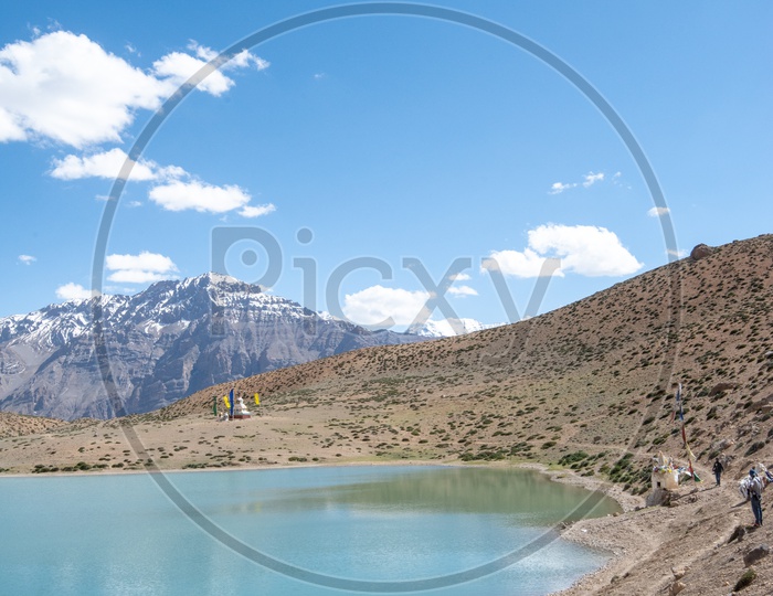 Tourists at Dhankar lake with mountain peaks in the background in Spiti Valley