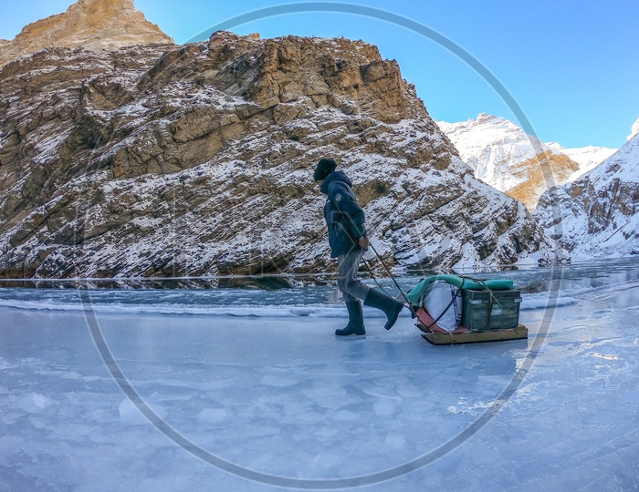 An Adventurer Walking In The Frozen Zanskar River Valleys With Snow Capped Mountains in Background