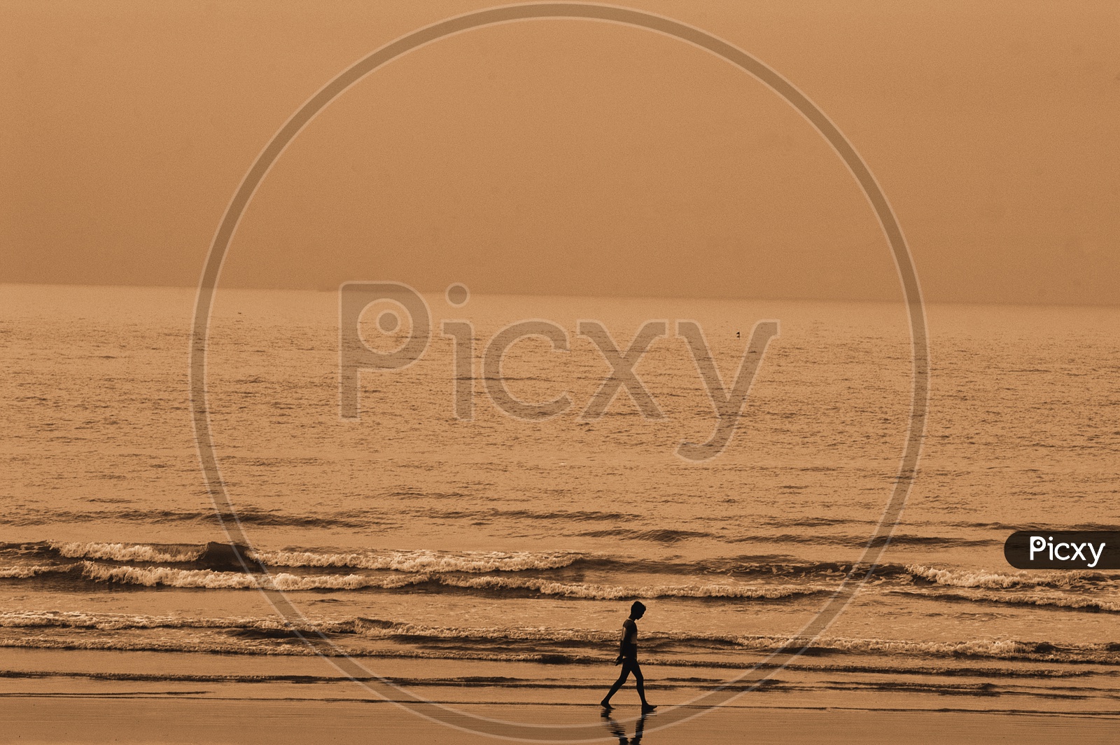 Silhouette of a boy walking along the sea shore in a beach