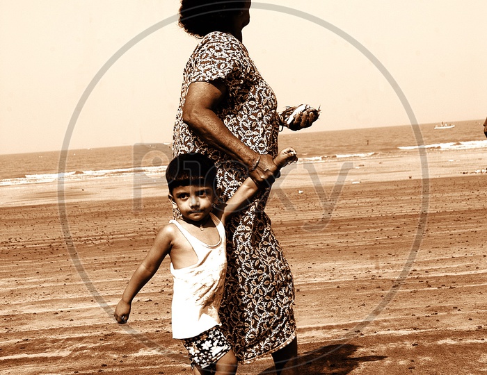 A grandmother holding her grandson and walking in the sand