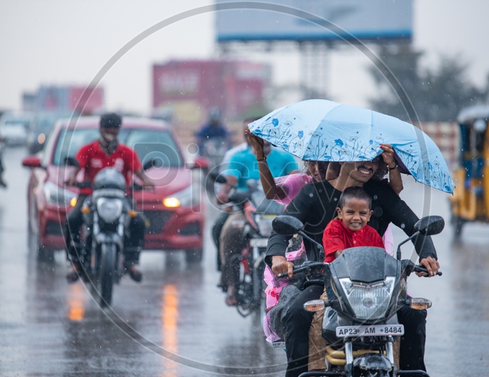 A Happy Family Commuting On a Motor Bike on a  Rainy Day