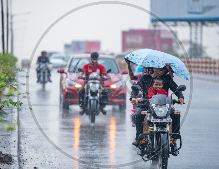 A Happy Family Commuting On a Motor Bike on a  Rainy Day