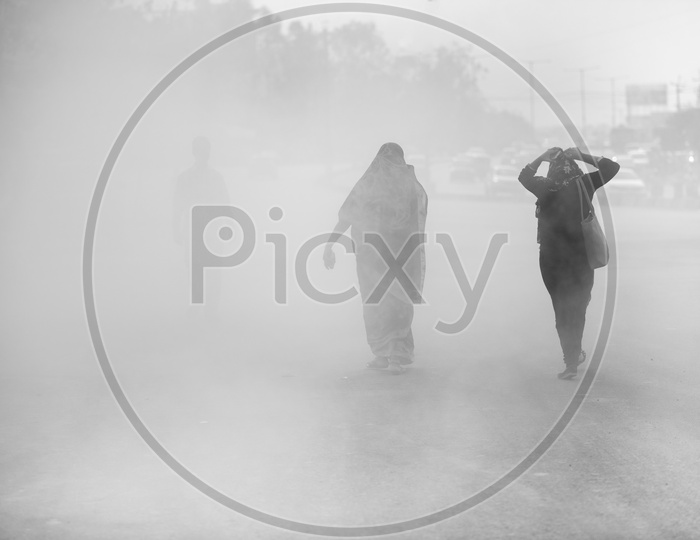 Pedestrains Walking Through a Thick  Dust  on Roads