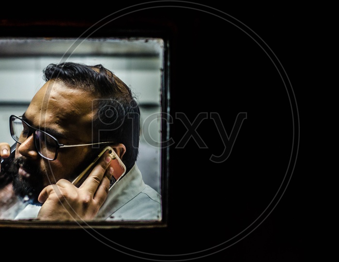 An Indian Man Speaking In Mobile Phone On Both Ears