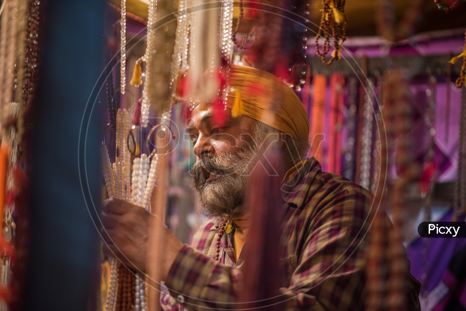 A Sikh man buying pearls jewellery from a vendor stall