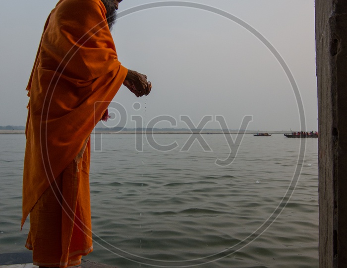 Indian Hindu Sadhu Or Baba Performing Pooja To Holy River