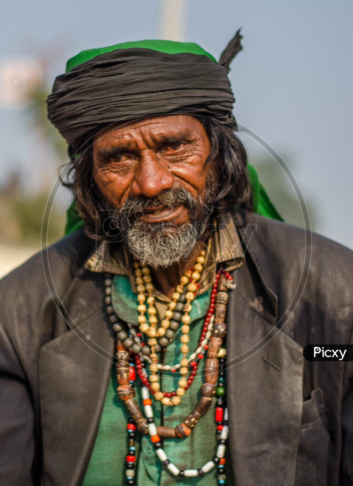 Portrait of an Indian man with black turban and wearing beaded chains