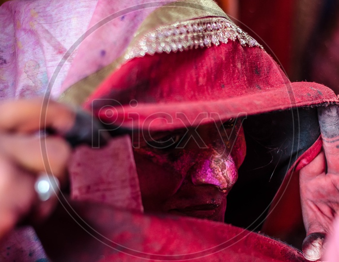 Color Filled Faces Of Indian Woman Behind Veil in Lathmar Holi Festival