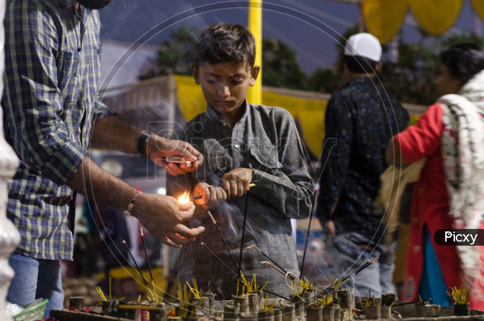 An Indian Boy Lighting The Scent Sticks at a Worships Place