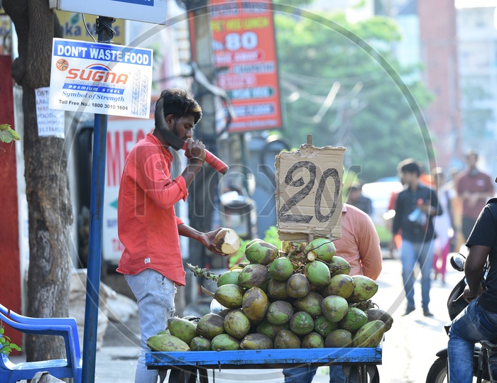 A Coconut Vendor Chopping Coconut At a Roadside Stall