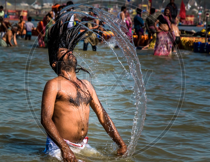 A Devotee Making a Water Splash With His Long Hair In River Water During Taking Bath In River At  Kumbh Mela