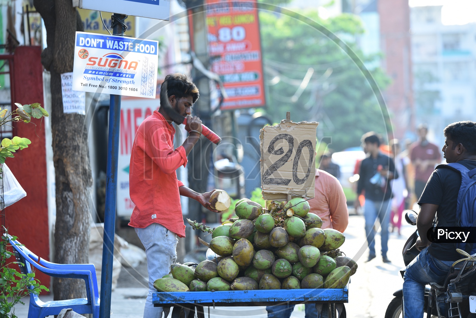 A Coconut Vendor Chopping Coconut At a Roadside Stall
