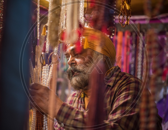 A Sikh man buying pearls jewellery from a vendor stall
