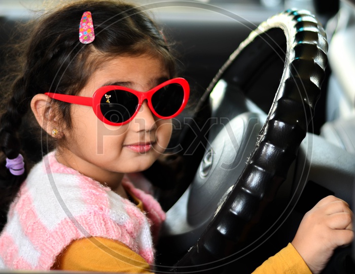 A Young Girl Child Holding a Car Steering Wheel