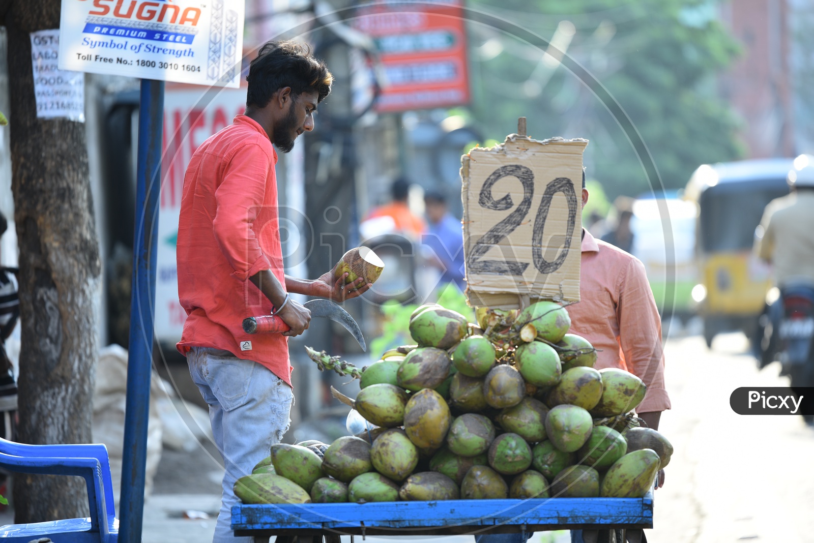 Image of A Coconut Vendor Chopping Coconut At a Roadside Stall-YG631226