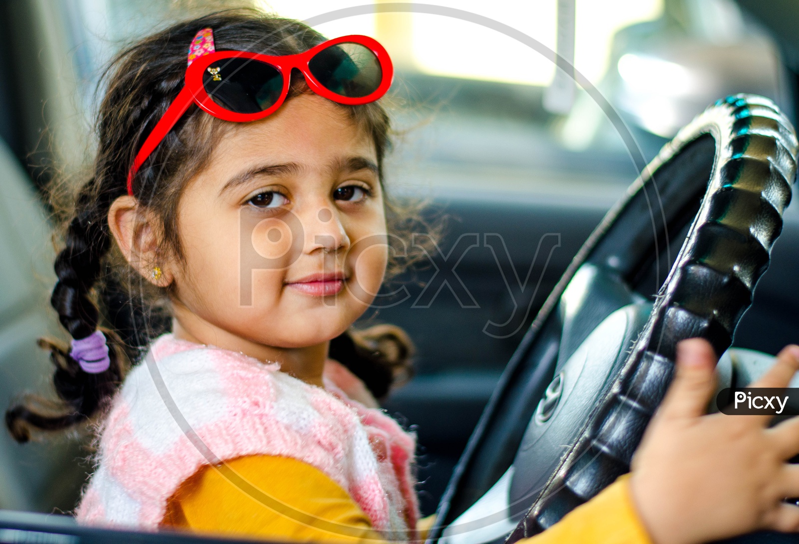 A Cute Little Girl Holding Car Steering Wheel