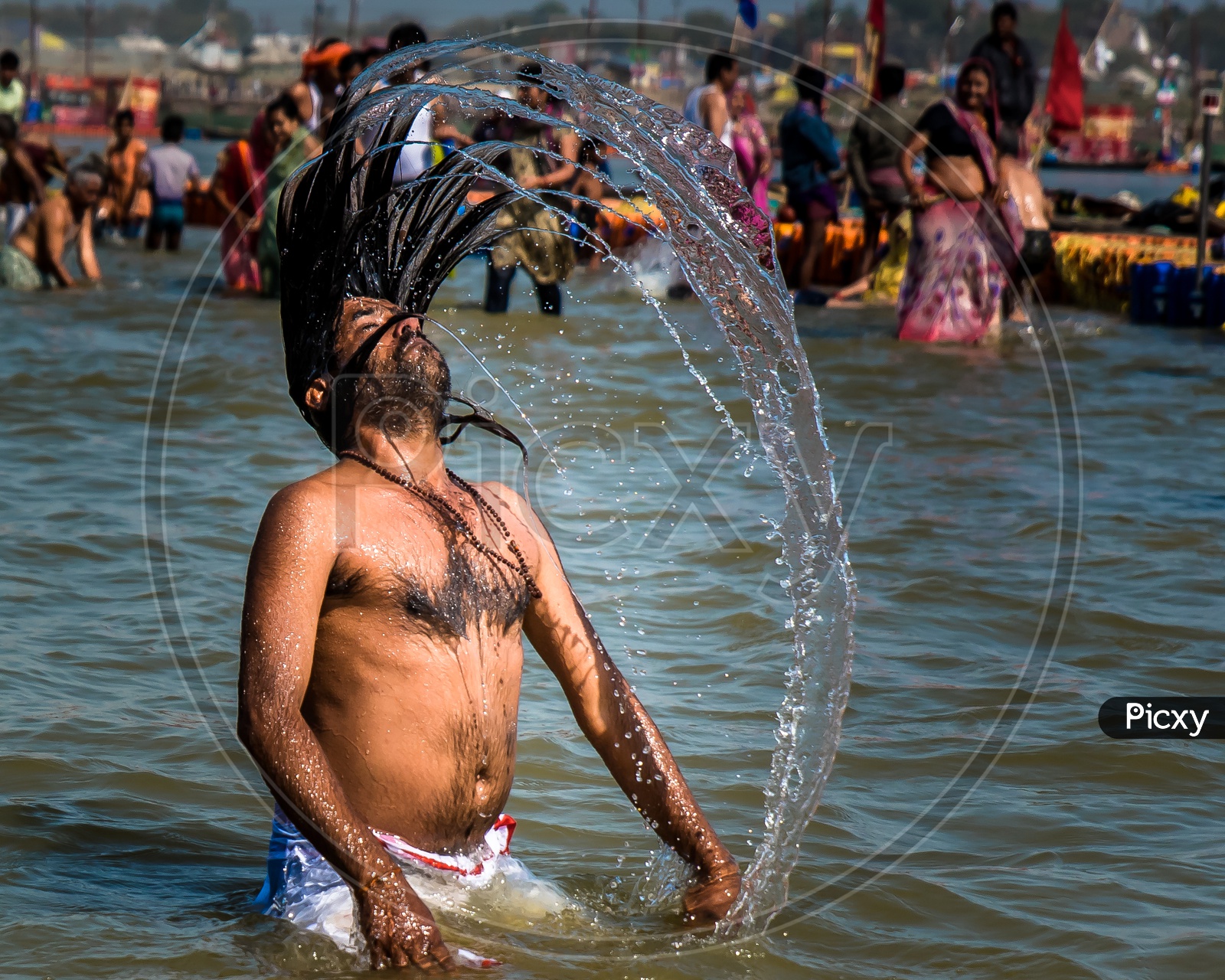 A Devotee Making a Water Splash With His Long Hair In River Water During Taking Bath In River At  Kumbh Mela