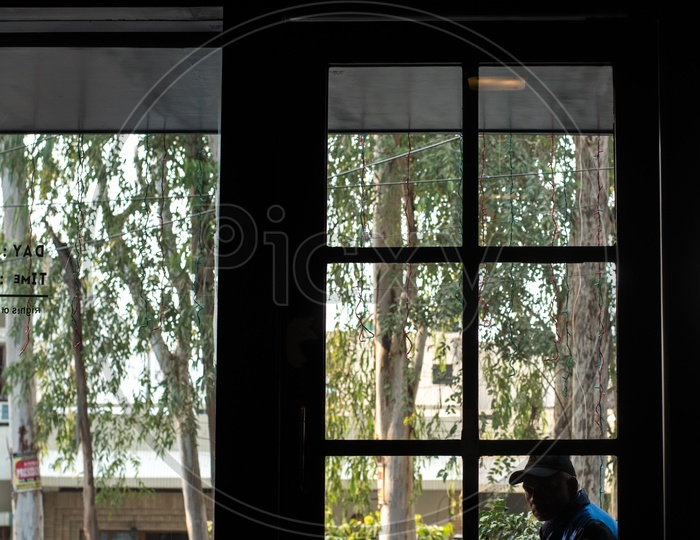 A man seen through a window who is sitting outside a room