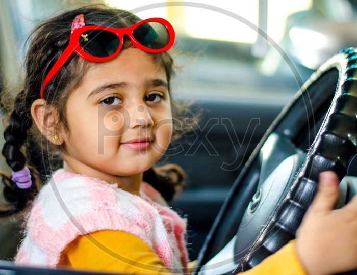 A Cute Little Girl Holding Car Steering Wheel
