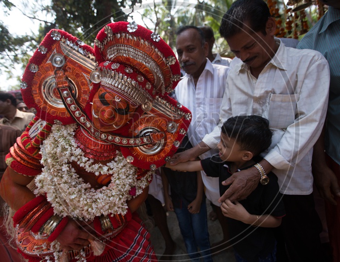 A kid touching the Theyyam Performer