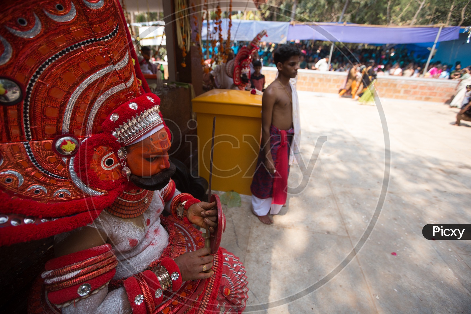 A performer in colourful costume, face mask, during a performance of Theyyam