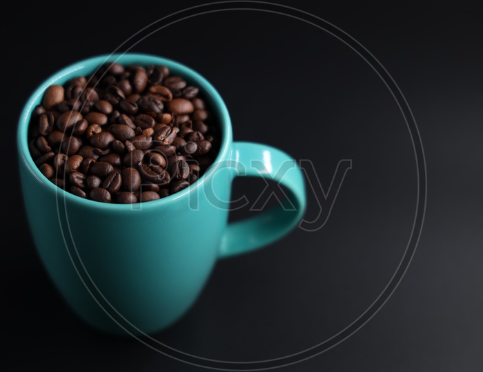 Coffee Beans In a Coffee Mug  Composition Shot On An Isolated Black Background