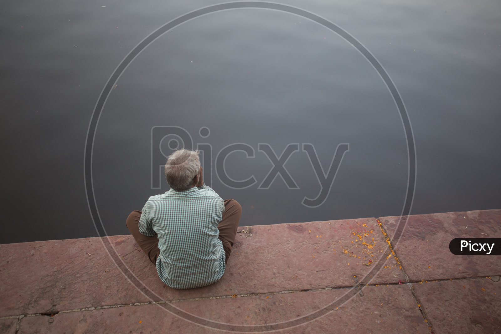 An elderly man sitting by the water side