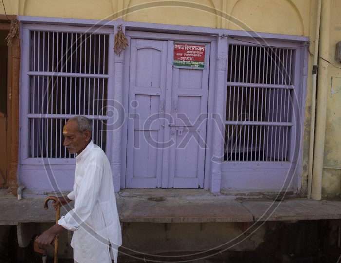 An old man walking with a stick in the streets of Barsana