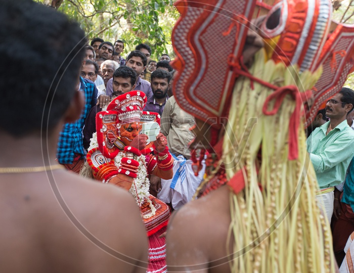 A Theyyam performer in colourful costume with a mirror