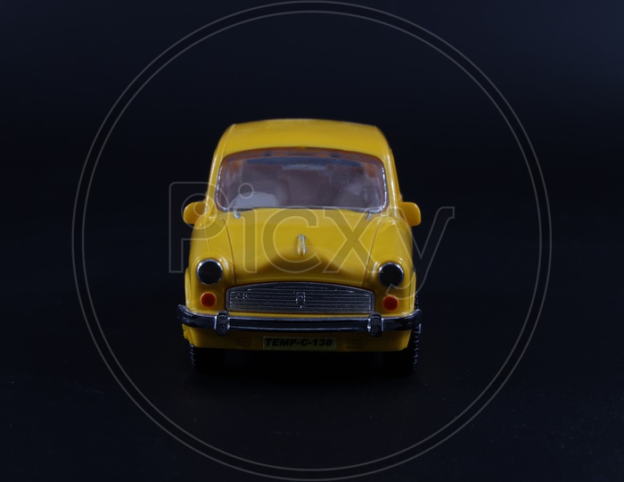 A Yellow Taxi Or Car Or Cab  Toy  Composition Shot On an  Isolated Black Background