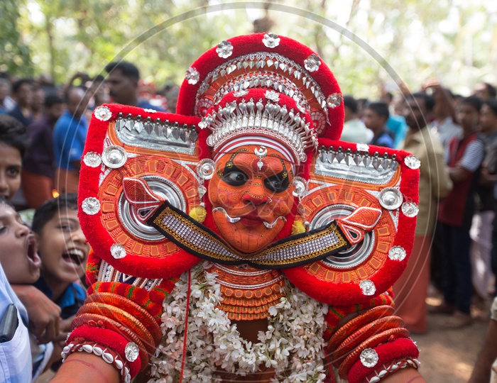 A performer in colourful costume, face mask, during a performance of Theyyam