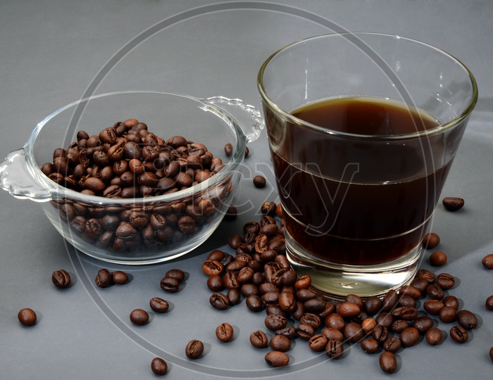 Roasted Coffee beans in a bowl with a glass of black coffee