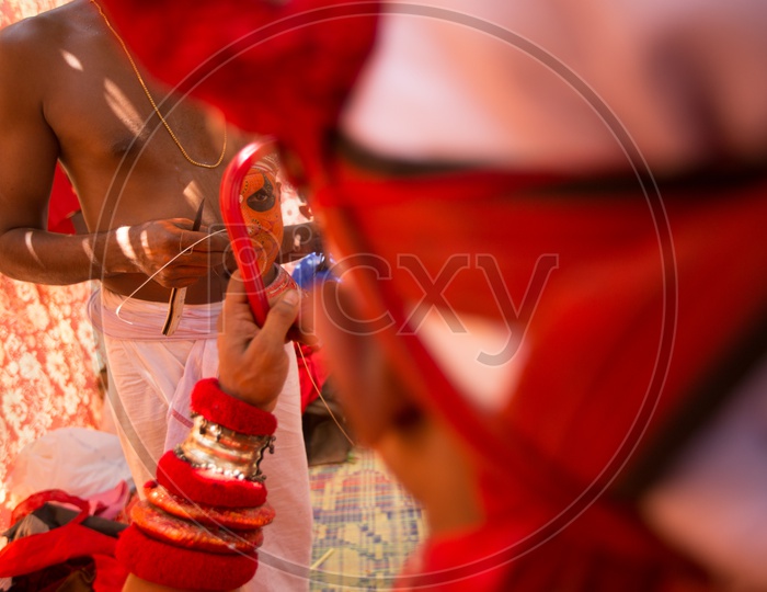A Theyyam performer looking in the  mirror