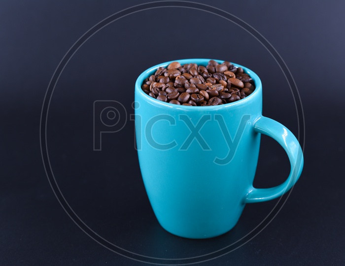 Coffee beans in a blue coffee mug on a dark background