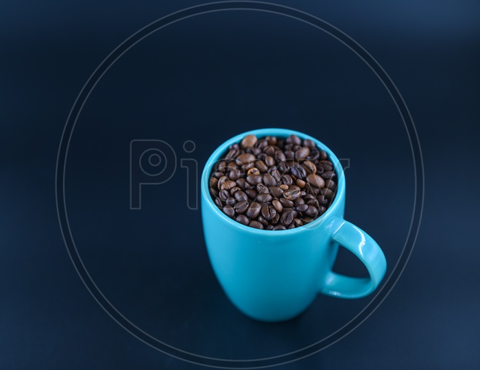 Coffee Beans In a Coffee Mug Composition Shot Over an Isolated Black Background