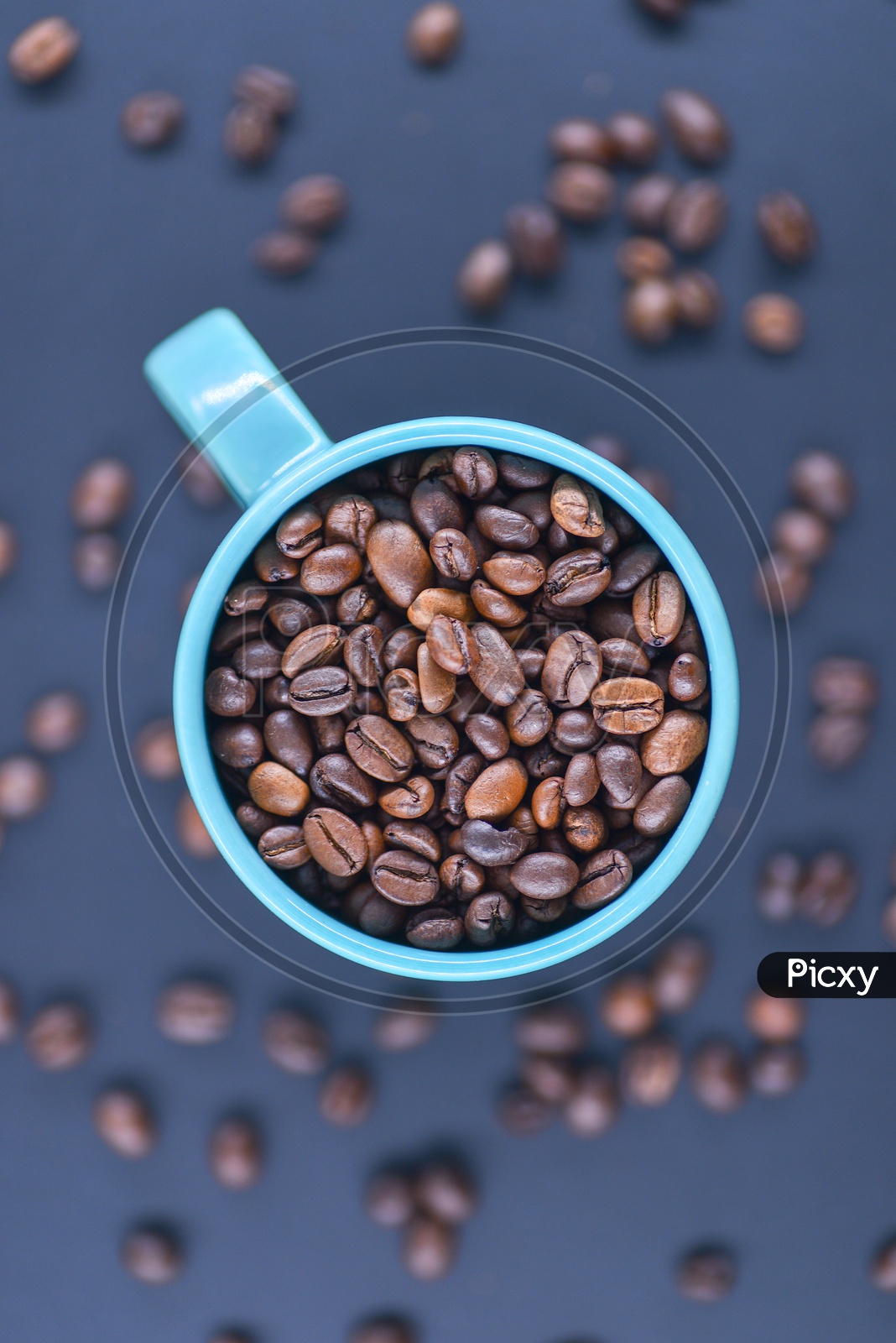 Coffee beans in a blue coffee mug on a dark blue background