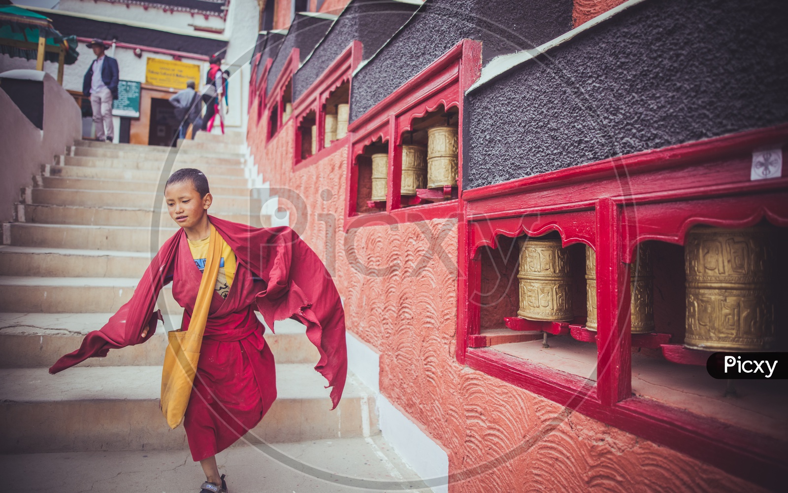 image-of-a-young-monk-walking-alongside-the-prayer-wheels-ar733425-picxy