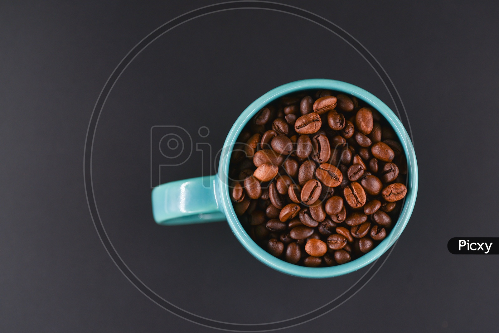 Coffee beans in a blue coffee mug on dark background