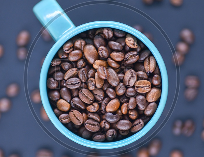 Coffee beans in a blue coffee mug on a dark blue background