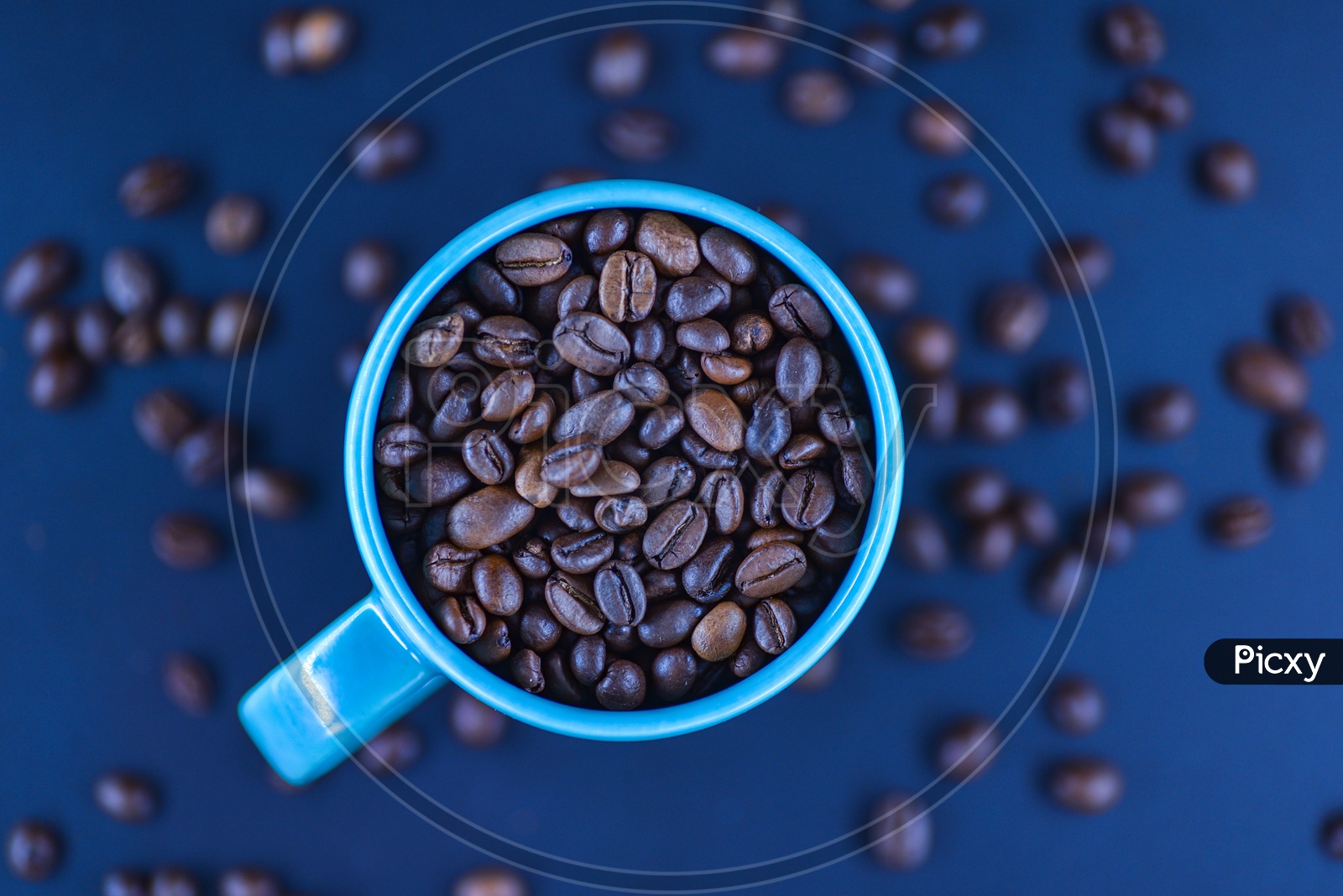Coffee Beans In a Coffee Mug With Scattered Coffee Beans In Background
